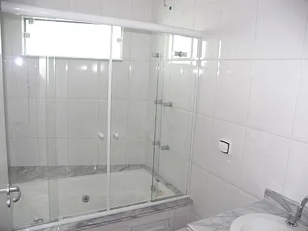 Box de vidro sobre banheira instalado em banheiro moderno